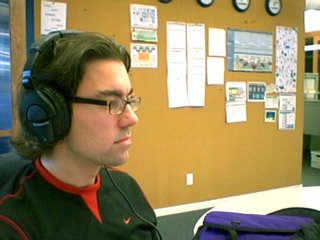 [Derek wears big Sennheiser headphones at work