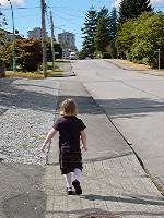 [Girl walking away up a suburban street]